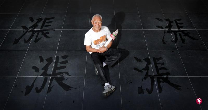 《联合早报》2011年首次主办“字述一年”投选活动，邀请了惯用大毛笔蘸水在地上练习书法的陈扩业老先生，写出年度汉字“涨”。（档案照） 