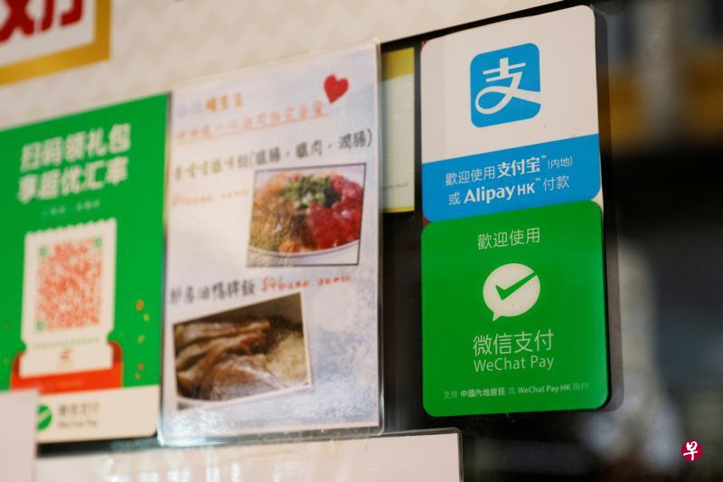上月初香港一家餐厅玻璃门上展示了阿里巴巴的支付宝，以及腾讯的微信支付二维码，供顾客消费支付。（路透社）