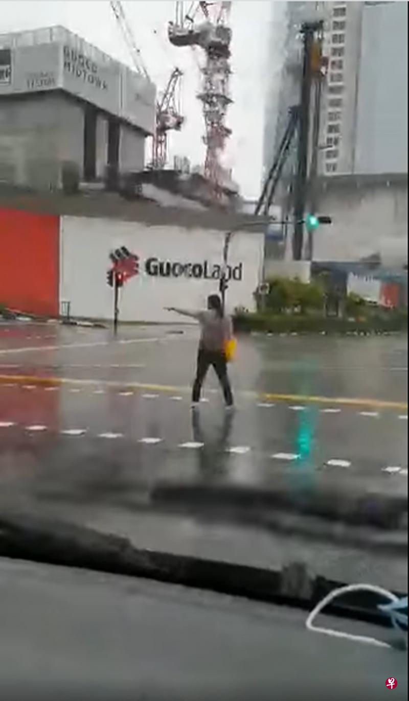 女子不知何故冒雨站在繁忙的交界处挡着车辆前行。（取自面簿)  
