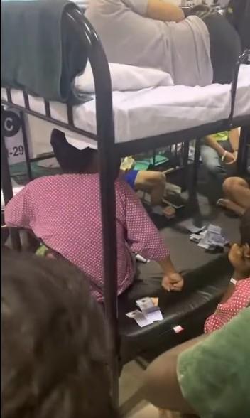 疑似沙登农业博览馆（MAEPS）冠病隔离中心的隔离者在床铺聚赌，床上还放着扑克牌与现金。（面簿视频截图） 