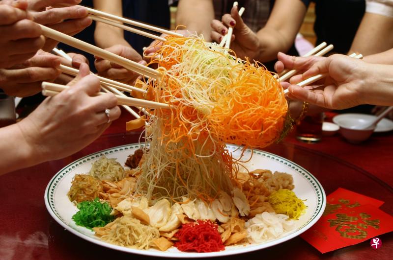 今年的农历新年，国人“捞起”时必须戴上口罩，也不应在加入鱼生每一种配料的时候喊出传统吉祥祝语。（档案照片）