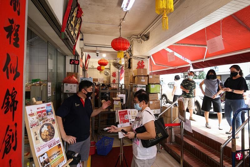 香港街老字号海味铺“德生”从两周前开始发放号码牌，以控制人流，商店旁也摆放了椅子供年长顾客坐下等候。（李健玮摄）