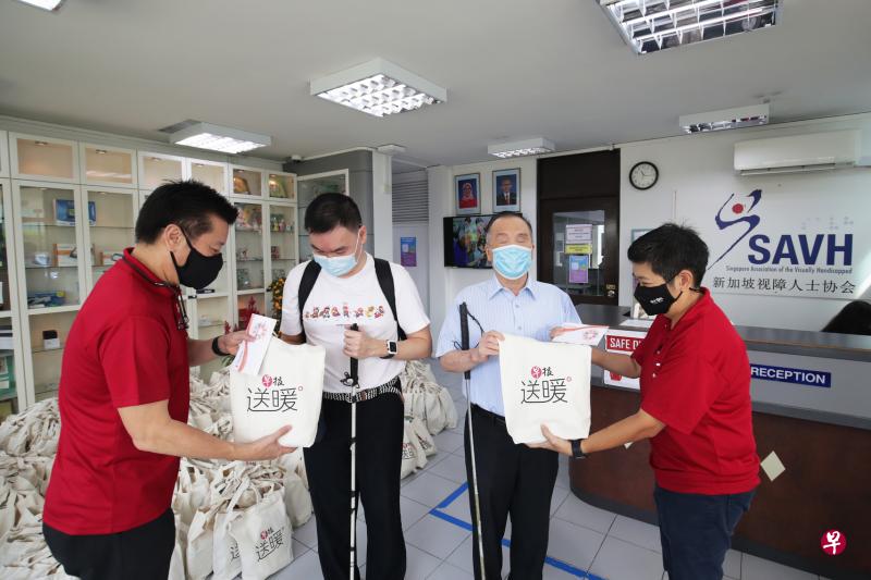 《联合早报》总编辑吴新迪（左一）以及新加坡报业控股华文媒体集团新闻中心总编辑韩咏梅（右一）昨天上午将363份价值各近80元的礼包，交给新加坡视障人士协会。（蔡家增摄）