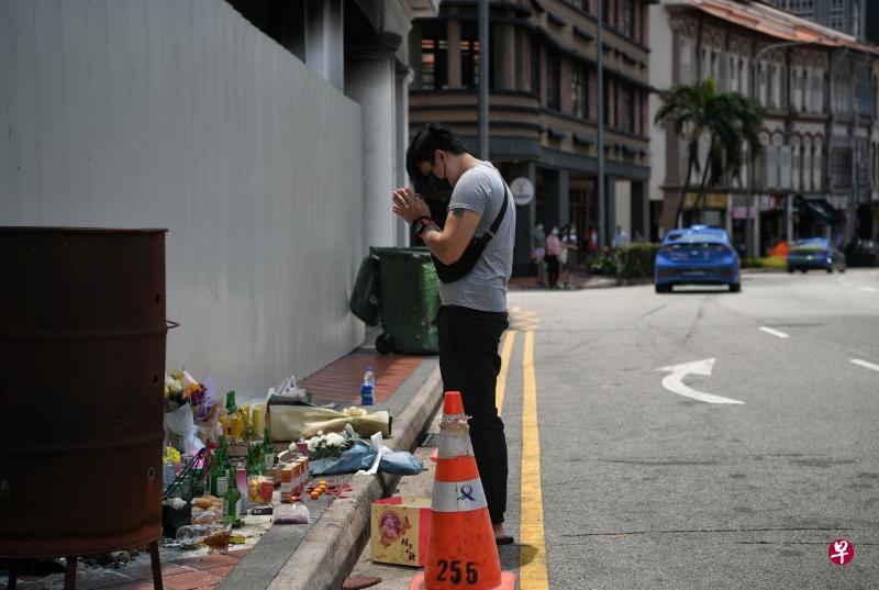 死者的朋友重返致命车祸现场，双手合十为亡友祷告。人行道上有人放了几束鲜花，还有五杯奶茶和五盒香烟等，祭奠五名死者。（海峡时报）