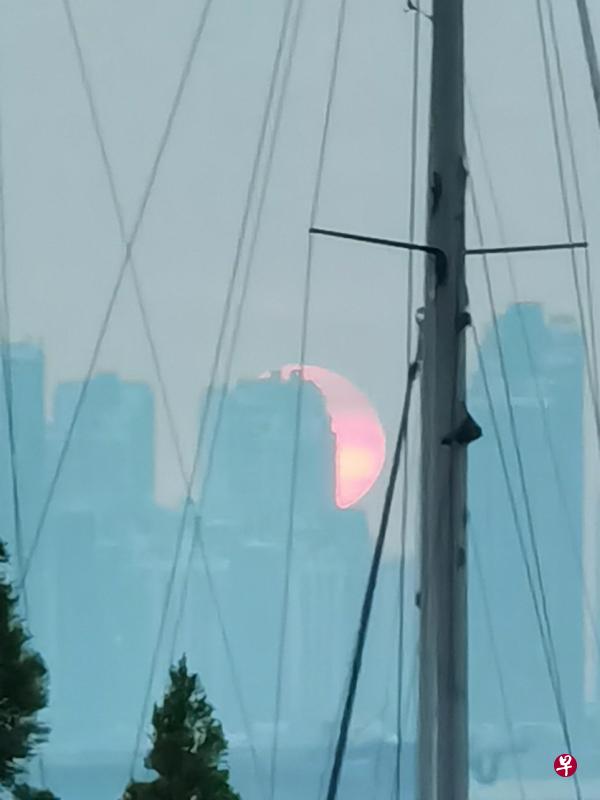 柔佛海峡对岸建筑物后方的日落。（梁丽庭摄）