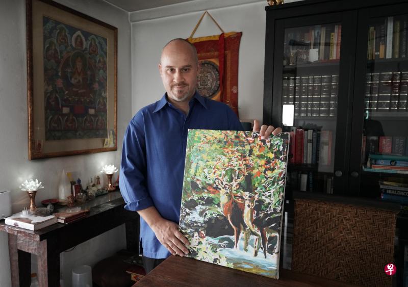 马克展示妻子陈淑铃生前完成的其中一幅画作。（谢智扬摄）