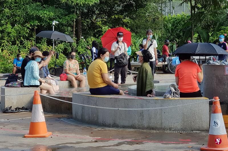 披着绿色毛巾的妇女下半身浸泡水中，工作人员多次劝说无果。（蔡振鸿摄）