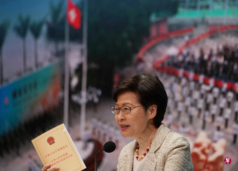 香港特首林郑月娥昨天在记者会上手持一本香港《基本法》，强调港府将全力配合选举制度改革方案。（路透社）