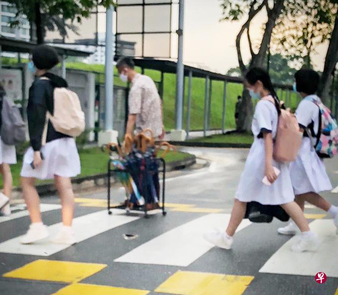 朱义顺在雨天替学生供伞。（取自网络） 