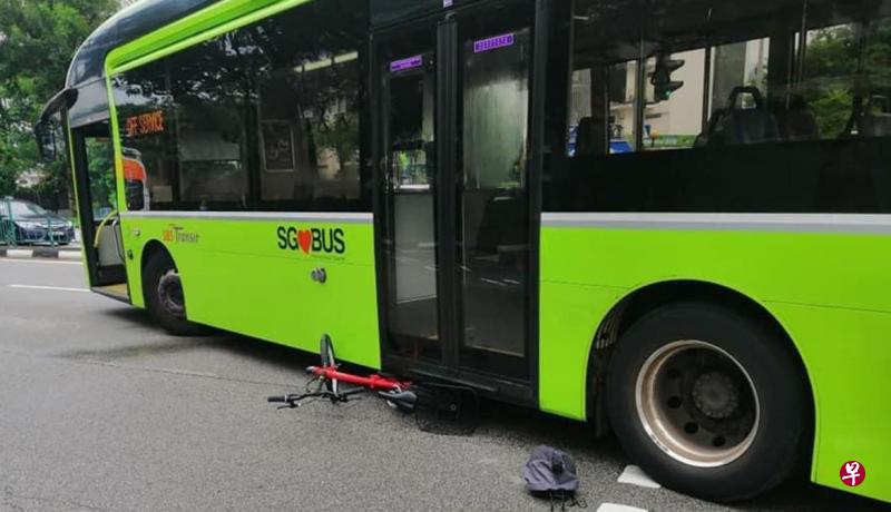 脚踏车被撞后卡在巴士车底，有个安全帽掉落在一旁。（取自SG Road Vigilante面簿） 
