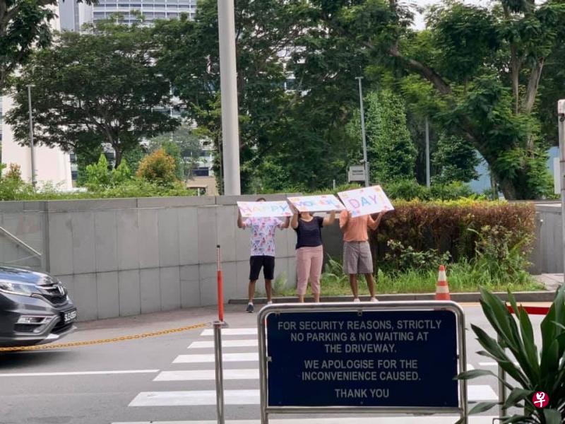 3人酒店外举牌，祝母亲“母亲节快乐”。（取自网络） 