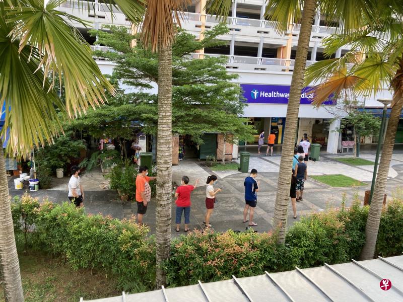 今早在同座组屋楼下诊所外排队检测的居民，一度多达50人，人龙排到组屋外。（唐家鸿摄） 