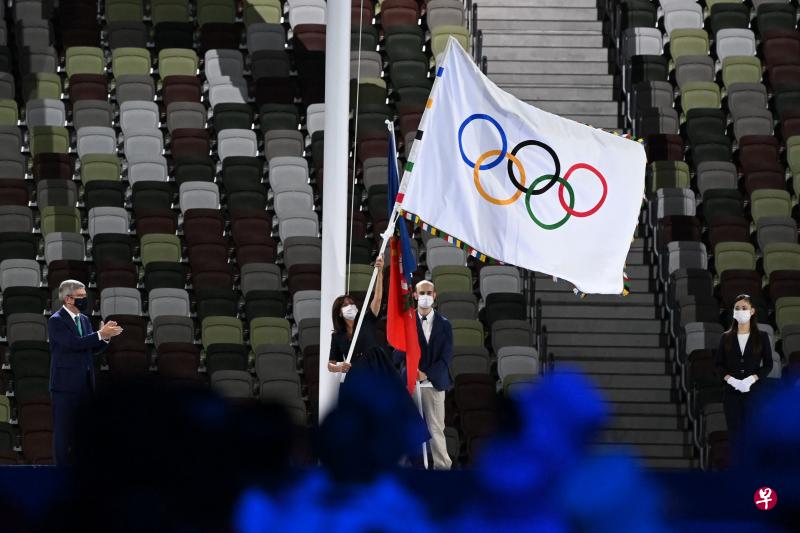 巴黎市长伊达尔戈从国际奥委会主席巴赫手中接过这面装饰有奥运五环的旗帜后，然后挥舞着旗帜。（法新社） 