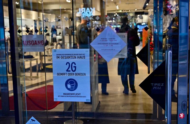 柏林一家商店门口贴的海报显示，只允许完成冠病疫苗接种者或冠病痊愈者进入，并强制规定进入者必须戴口罩。（法新社） 