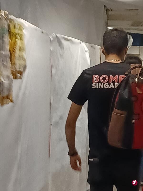男子穿着一件写有“炸新加坡”（Bomb Singapore）字眼的衬衫，在地铁站隧道走动。（受访者提供） 