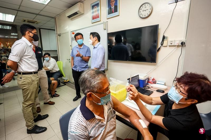 黄循财（右一）和王乙康（右二）走访位于义顺中第三分区居民委员会的流动接种中心。（叶振忠摄） 