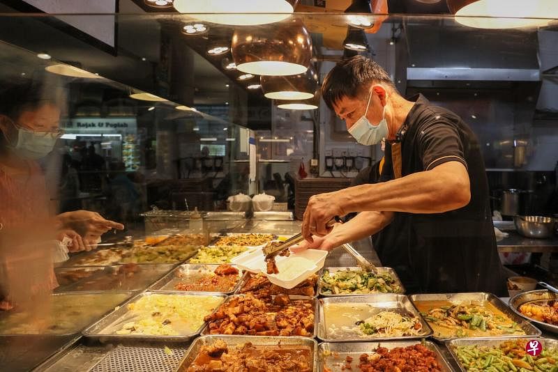 小贩等餐饮工作人员在处理食物时仍须戴口罩，或是餐饮专用的防飞沫透明口罩，以维持良好的卫生标准。（卓祾祎摄） 