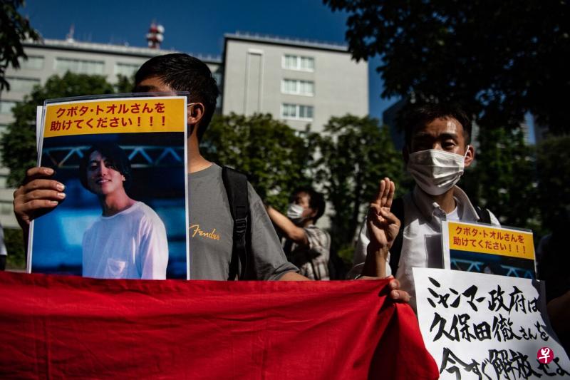 缅甸法院以违反移民法的罪名，判处在缅甸拍摄示威活动纪录片的久保田彻多三年的刑期。图为一群民众7月21日在日本东京，手持久保田彻的海报到日本外交部前游行。（法新社） 
