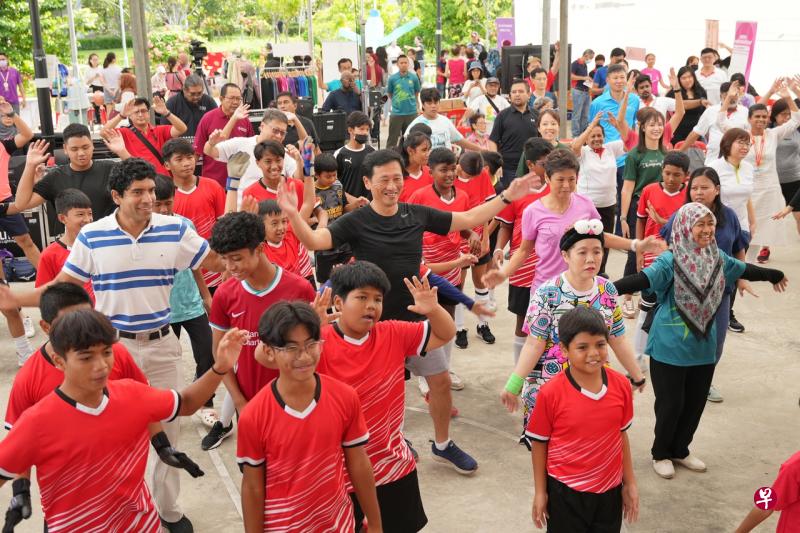卫生部长王乙康（身穿黑衣，中）与三巴旺集选区议员和居民在健走开始前，一同做热身运动。（谢智扬摄） 