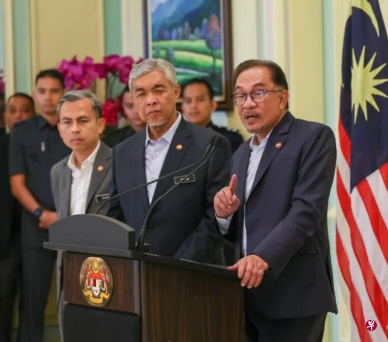马国首相安华（右）星期三在内阁会议后的记者会宣布，东海岸铁路项目照跑，但成本减少超过110亿令吉。中为副首相阿末扎希，左为数码通讯部长法米。（马新社） 