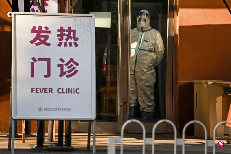 图为12月28日一名身穿防护服的安保人员在北京一家发热门诊门口站岗。（法新社） 
