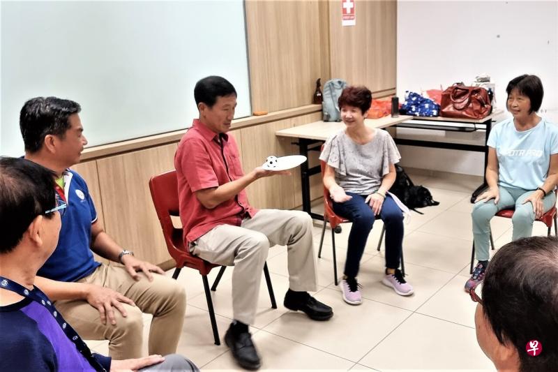 保健促进局和人民协会将扩大“乐享灿烂年华”计划 （Live Well, Age Well），在全岛活跃乐龄中心和民众俱乐部推出一系列活动，让年长者保持身心健康和社交。卫生部长王乙康（中）今早就在后港茨园民众俱乐部与参与项目的年长者互动。（王康威摄） 