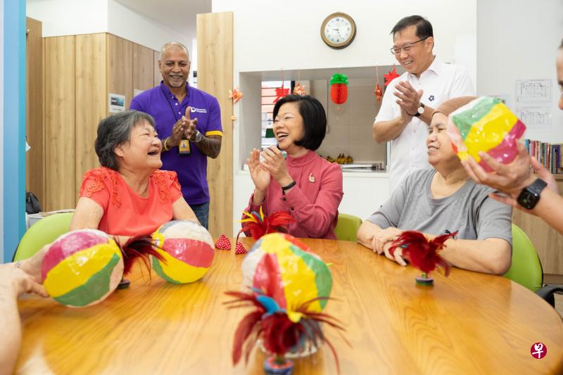 国家发展部兼外交部高级政务部长沈颖（中）星期一（2月13日）为社区事务署和新加坡失智症机构展开的合作项目主持推介，和日间护理中心的失智症患者们互动。后排右一为新加坡失智症机构总裁符祥明。（特约摄影张荣摄） 