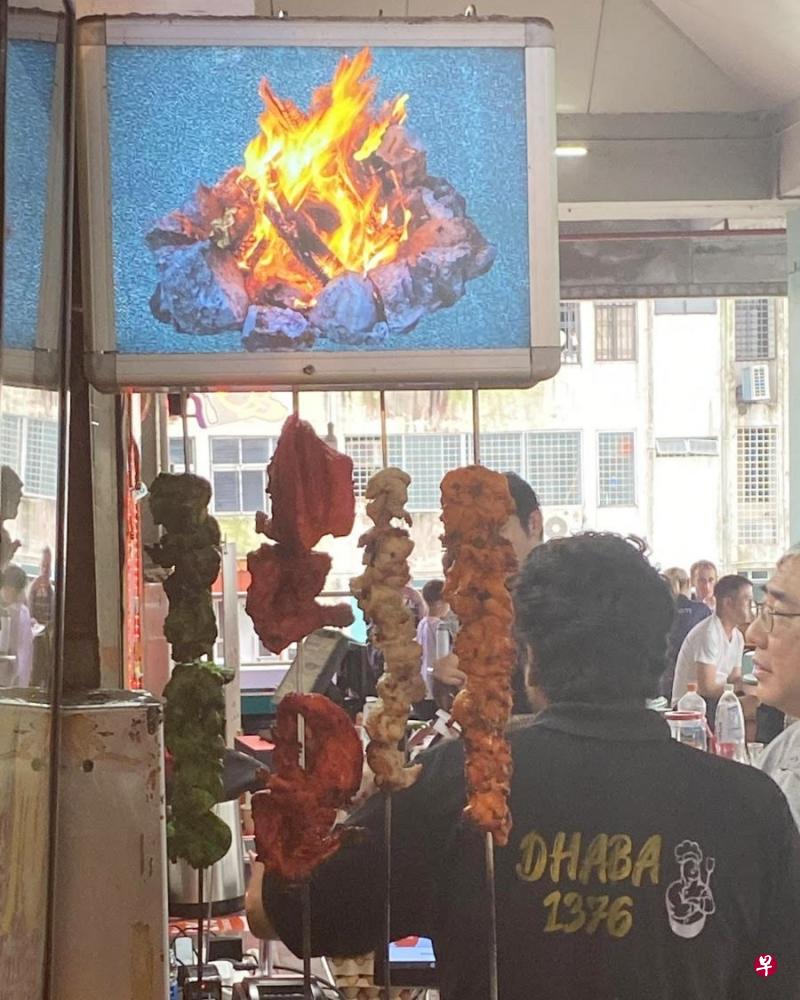 食客看见烤肉串挂在布满灰尘的招牌，直呼不卫生。（读者提供） 