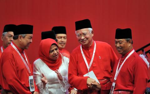 2015年12月，时任首相及巫统主席的纳吉（右二）在巫统大会上与署理主席慕尤丁（右一）握手。当时慕尤丁已被革除副首相职，两人在台上互动显得十分尴尬。左起是取代慕尤丁出任副首相的巫统副主席阿末扎希，以及妇女组主席莎丽扎。（档案照片）