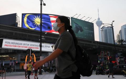 马来西亚一名戴着口罩的女子，2021年9月6日步行路过吉隆坡市区一条繁忙的街道。（路透社）



