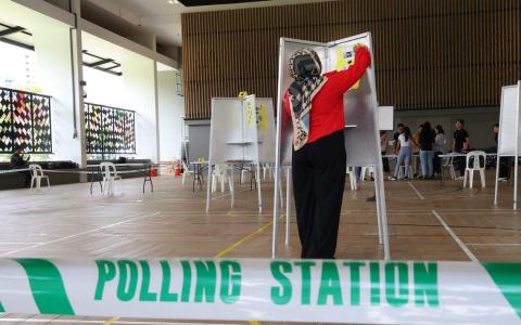 全岛1264个投票站星期四（8月31日）下午已经准备就绪，投票日上午8时开放给选民投票。图为选举工作人员在芽笼士乃民众俱乐部为投票亭贴上投票须知。（林明顺摄）