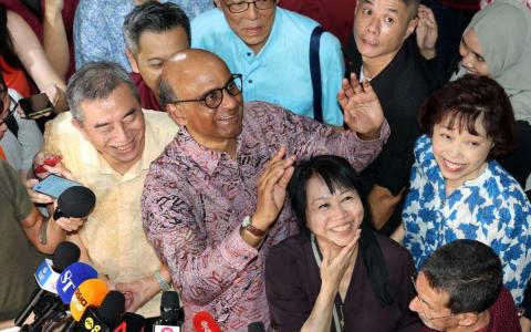 尚达曼（中）与妻子珍一藤木（黑衣）在达曼裕廊巴刹和熟食中心，与支持者一同等待总统选举结果揭晓。（邝启聪摄）