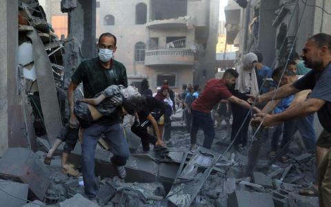 以色列连日持续空袭加沙地带，图为加沙南部城市汗尤尼斯一处民宅10月19日被击中后，大人把一个受伤孩子抱离废墟。（路透社）