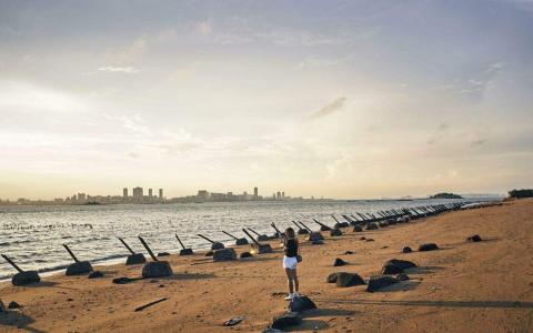 隔着台湾海峡遥望大陆厦门城市风景线的台湾金门岛，海滩上布满了防御桩。台湾总统选战进入倒数一个月，各阵营纷纷抛出两岸愿景，“战争与和平”“民主与专制”等话题交锋不断。（彭博社）