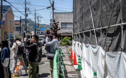 山梨县富士河口湖镇是另一个受到过度旅游问题困扰的地方，游客为了在这个热门拍照地点拍摄富士山，经常无视交通规则。当地政府于是决定安装一个巨大的黑色屏障挡住富士山。图中拍照者后面就是还在建造中的黑色屏障，建好后将移到能够挡住富士山的位置。（法新社）