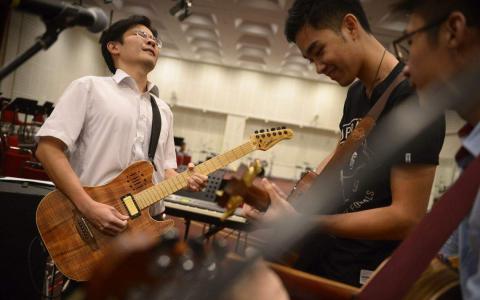 时任文化、社区及青年部长黄循财在2014年儿童慈善音乐会与年轻表演者同台演出前，到报业中心彩排。（档案照片）