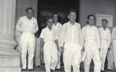 1959年6月5日，我国第一任总理李光耀（前排中）和他的八名内阁成员在宣誓就职仪式后，步出市政厅。（档案照片）
