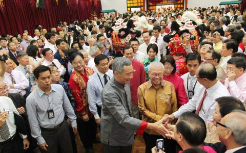 2012年1月25日，李显龙总理（最靠近镜头中央、穿灰色唐装者）以主宾身份出席新加坡宗乡会馆联合总会和通商中国联办的新春团拜。在他身旁一起和与会者握手贺年的是宗乡总会会长兼通商中国主席蔡天宝。（档案照片）