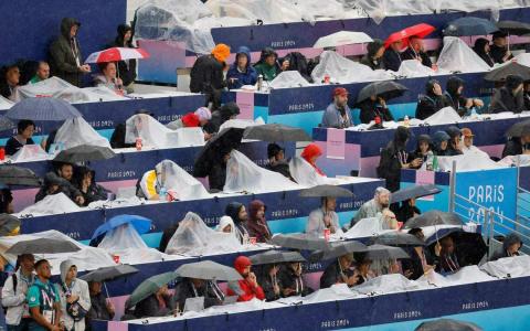 巴黎奥运会开幕式当天，记者们一边撑伞，一边打稿，好不狼狈。（路透社）