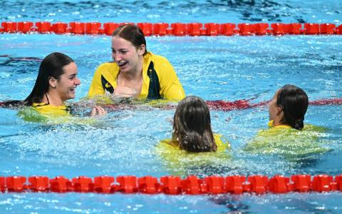 澳洲女泳将莫莉（左起）、艾玛、凯莉与詹娜领取奖牌后，穿着领奖服跳入水中庆祝。 （法新社）