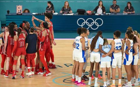 奥运女篮决赛结束，喜上眉梢的美国队（红衣）和黯然神伤的法国队形成鲜明对比。（法新社）