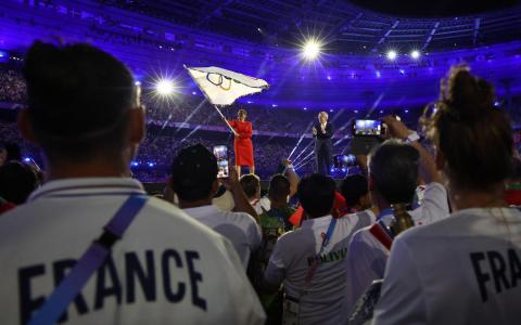 洛杉矶市长凯伦·巴斯（红衣）从国际奥委会主席巴赫手中接过奥运旗帜后挥舞，象征奥运会进入洛杉矶时间。（法新社）