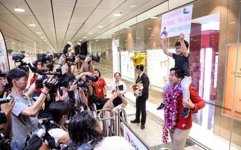 墨士廉让小粉丝陈昱恺骑在肩上，在镜头前合影。陈昱恺在海报上写着：“我今天翘课来见墨士廉。”（关俊威摄）