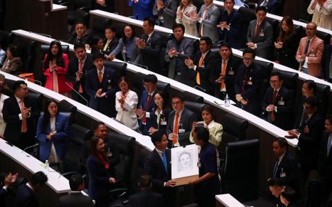 泰国宪法法院宣布暂停前进党党魁披塔（左）的国会下议院议员资格后，为泰党国会议员托萨蓬在披塔准备离场时送上一副披塔的肖像画以示支持。（路透社）