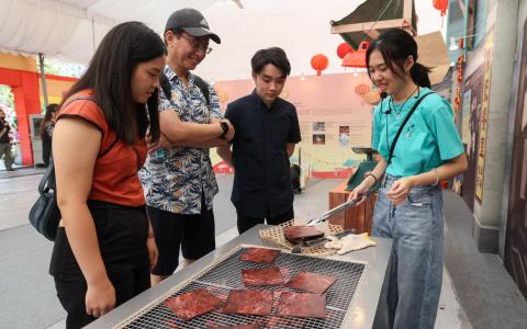 春到河畔年货市场迎新春展览，以互动元素和装置为特色，访客还能利用道具尝试自己动手“烤肉干”。 （卓祾祎摄）
