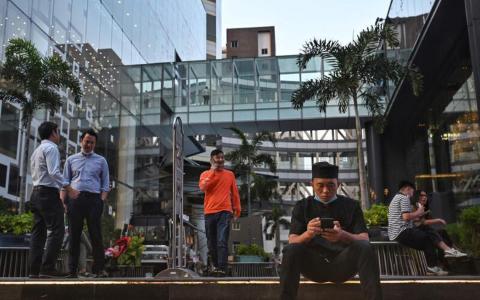 泰国目前的最低单日工资，在曼谷是353泰铢（约13.80新元），春武里府是354泰铢，其他地方都低于这个水平。图为商店员工和办公人员聚集在曼谷的一个购物中心外。（法新社）