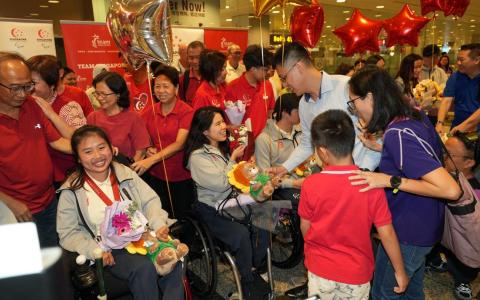 我国残奥会奖牌得主陈仪婷（坐者左）的父母陈文嘉（左）和吴玲梅（左二，部分被遮挡），以及叶品秀（坐者左二）的哥哥叶建良一家都来到机场欢迎我国团队回国。（谢智扬摄）