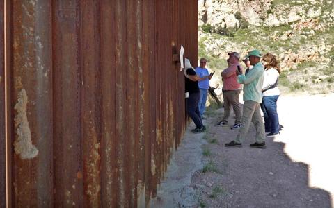 图森援人机构志愿者科楚雷克（左一）9月27日带着一支考察团到美国和墨西哥边境，从围墙的美国一侧望向墨西哥。（林国明摄）