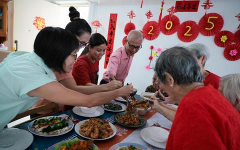 虽没有血缘关系但生活在一起，护工易伟（左三）和梅（左二）照顾四名居民的起居，也时常安排活动为老人家的生活增添色彩，包括煮大餐庆祝农历新年。红冠护理总监陈宝芬（左一）和护理协调员曾桂雄（左四）也和居民同庆。（张俊杰摄）