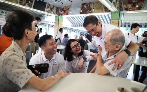 东海岸集选区原议员孟理齐博士（站立者）19日与人民行动党新人吴培铭（左二起）和何礼娜走访东海岸集选区。他早前已透露，自己负责管理的实乞纳区将由何礼娜接手。（关俊威摄）